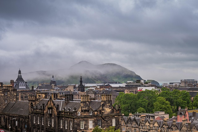 Scenic view of the Scottish countryside near Kinross with rolling green hills, soft morning mist and a charming stone cottage surrounded by wildflowers