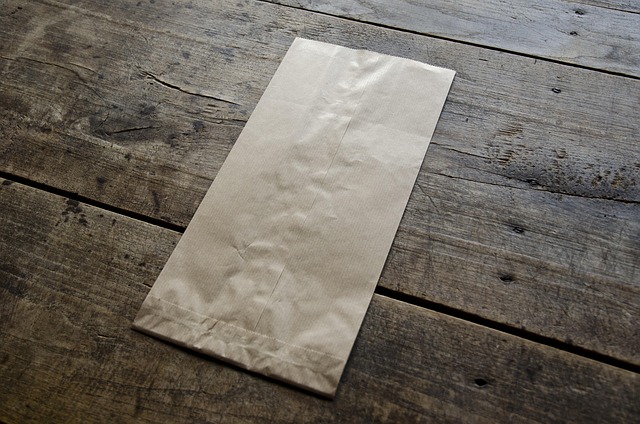 Eco-friendly gift packaging materials including recycled kraft paper, compostable tissue, cotton ribbon and dried wildflowers on a natural linen surface